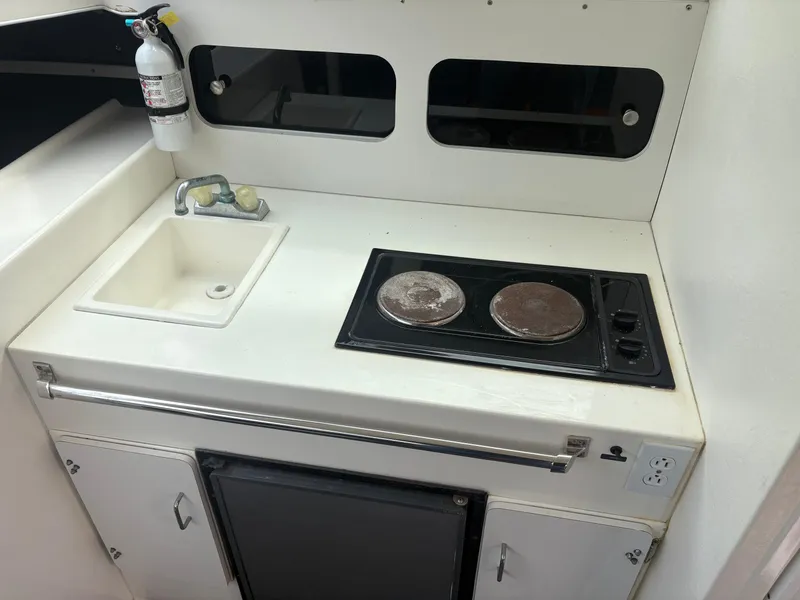 Slide: The Image of Compact kitchen area in a 1998 Penn Yan 269 Legend boat with stove, sink, and fire extinguisher. - 14