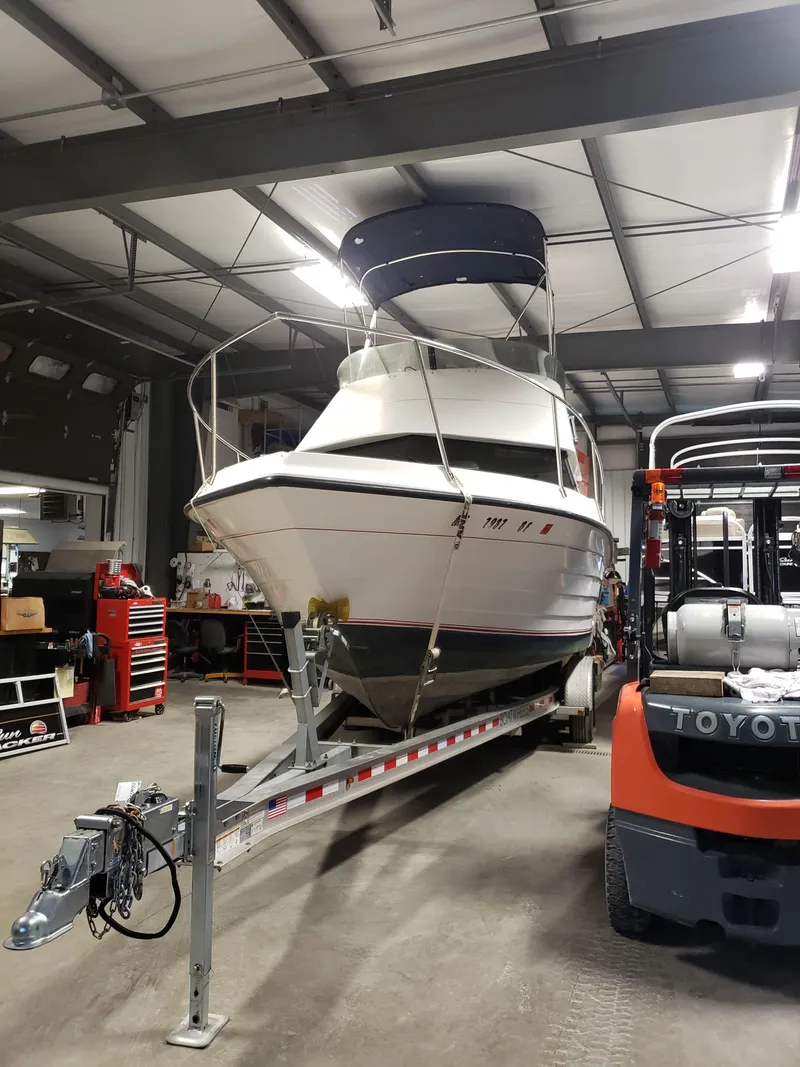 Slide: The Image of 1998 Penn Yan 269 Legend boat on trailer in a garage with forklift nearby. - 20