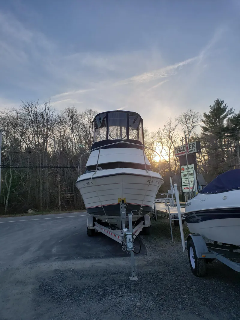 Slide: The Image of 1998 Penn Yan 269 Legend boat on trailer at sunset, parked near trees and signage. - 22