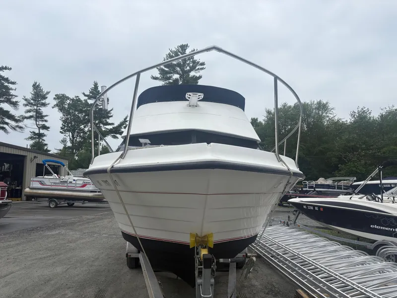 Slide: The Image of 1998 Penn Yan 269 Legend boat on trailer, surrounded by trees and other boats. - 3