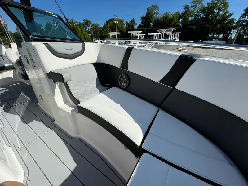 Slide: The Image of 2025 Chaparral 270 OSX boat interior with sleek white and black seating, docked outdoors. - 12
