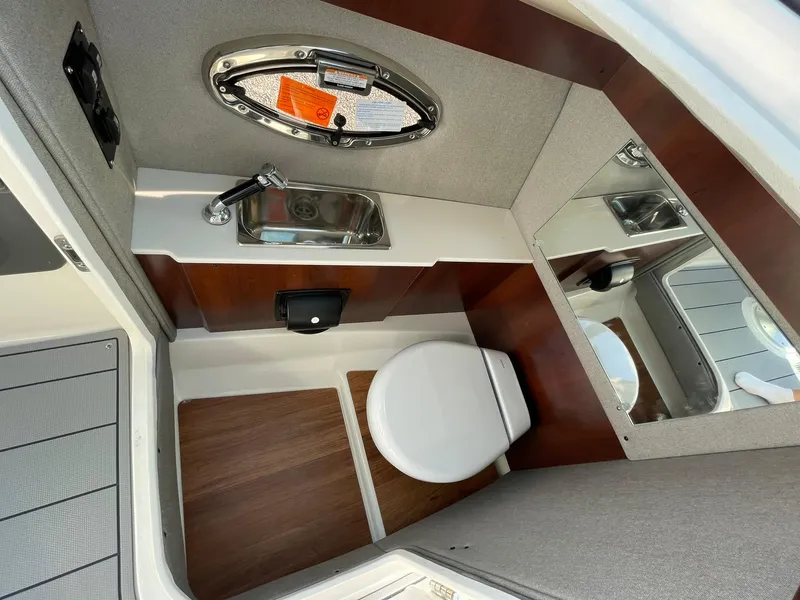 Slide: The Image of 2025 Chaparral 270 OSX boat interior bathroom with sink, toilet, and mirror. - 42