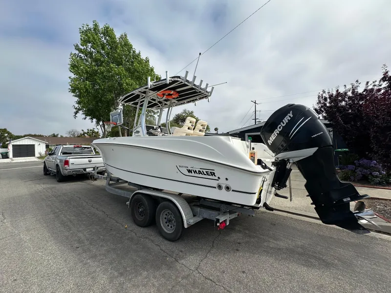 Slide: The Image of 2011 Boston Whaler 220 Outrage boat on trailer, parked on street with Mercury outboard motor. - 12