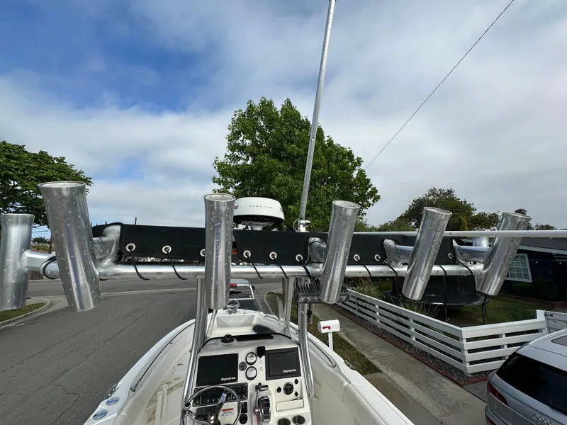 Slide: The Image of 2011 Boston Whaler 220 Outrage boat with rod holders, parked on a street. - 37