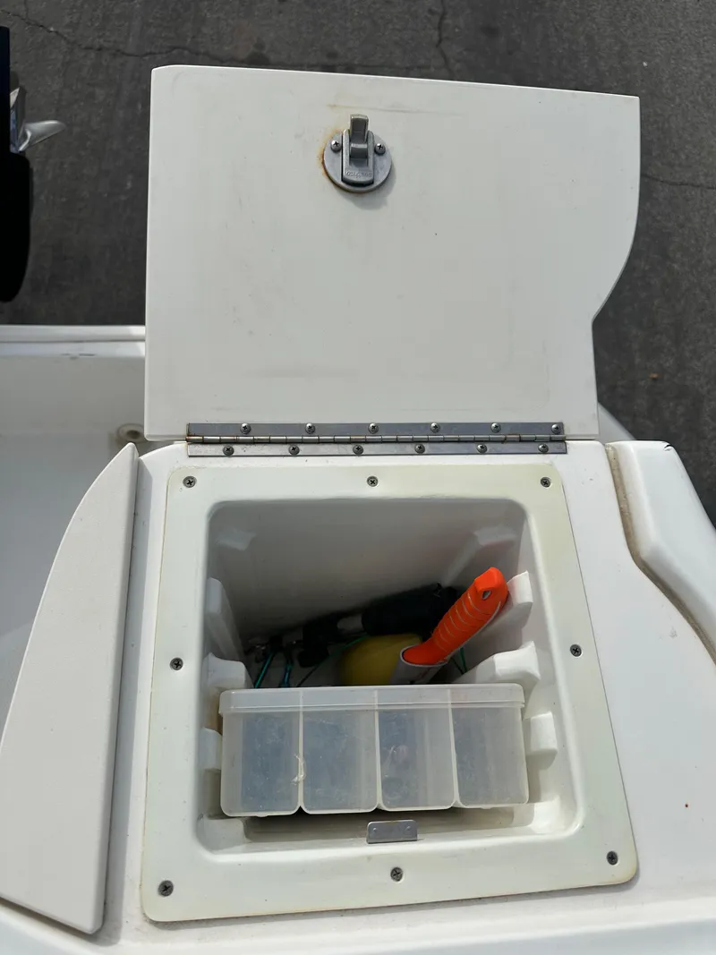 Slide: The Image of Open storage compartment on a 2011 Boston Whaler 220 Outrage boat, containing tools and accessories. - 39