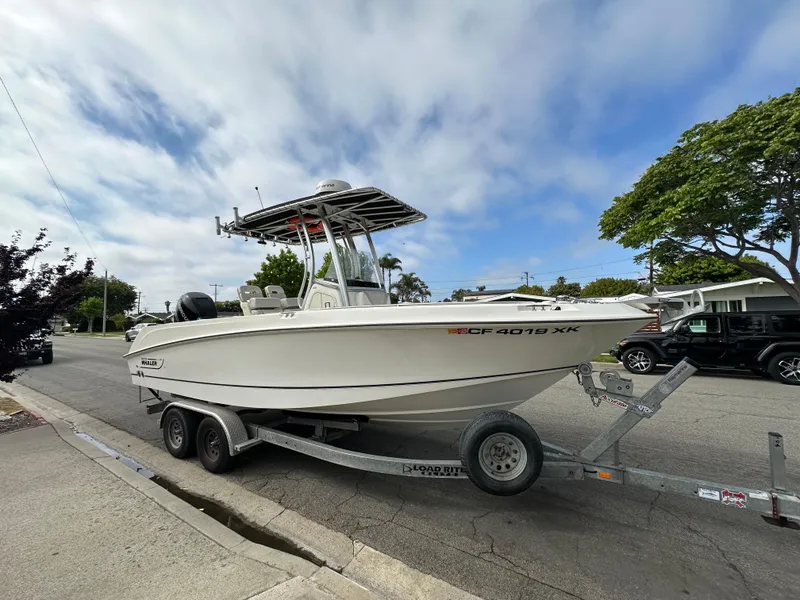 Slide: The Image of 2011 Boston Whaler 220 Outrage boat on trailer, parked on street under cloudy sky. - 7