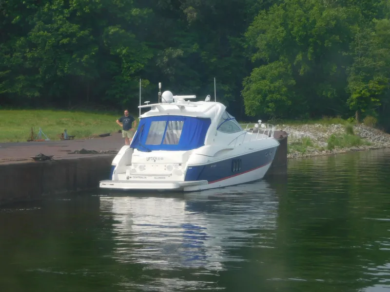 Slide: The Image of 2005 Cruisers Yachts 500 Express docked by a lush, green shoreline. - 2