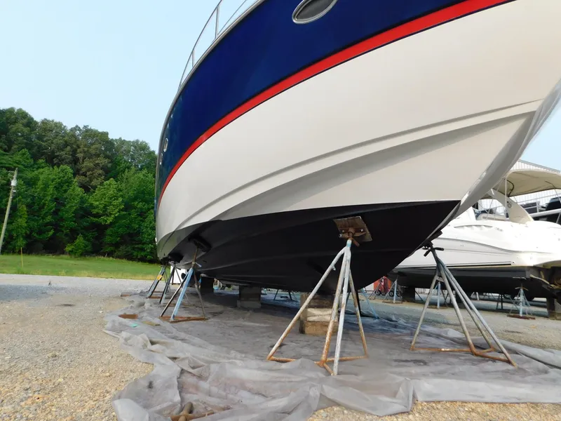 Slide: The Image of 2005 Cruisers Yachts 500 Express on stands, blue and white hull, outdoor storage. - 6