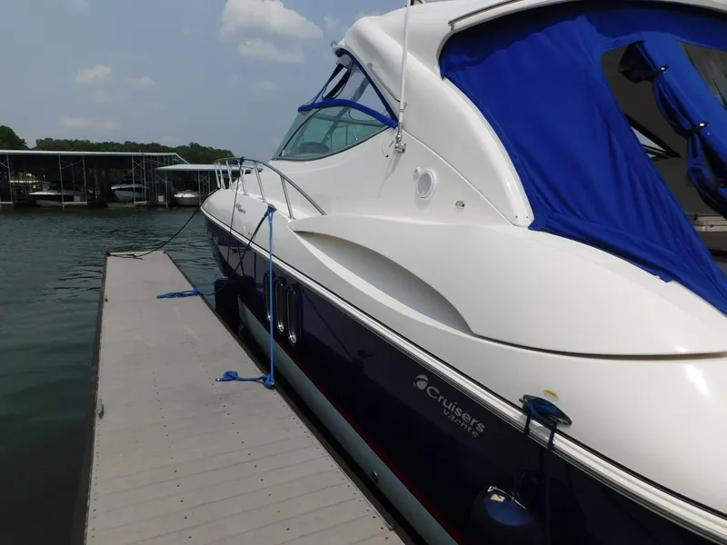 Slide: The Image of 2005 Cruisers Yachts 500 Express docked, featuring sleek design and blue canopy. - 16
