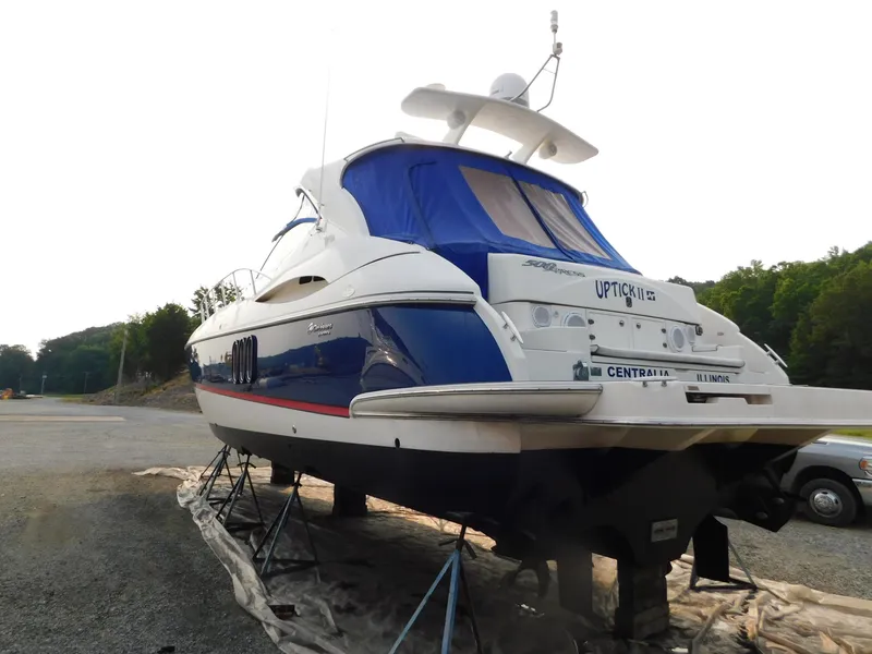 Slide: The Image of 2005 Cruisers Yachts 500 Express on stands, blue and white exterior, parked outdoors. - 8