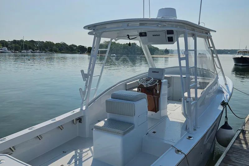 Slide: The Image of 1994 Tides 27 Sportfish boat docked on calm water, featuring a spacious deck and helm. - 2