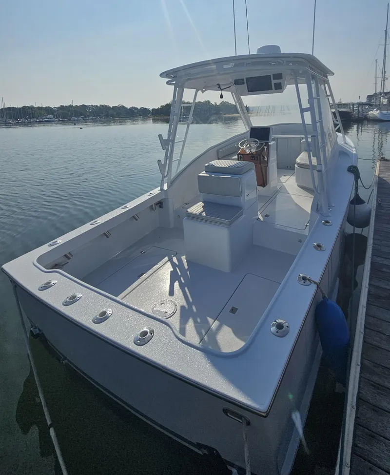 Slide: The Image of 1994 Tides 27 Sportfish boat docked in calm waters, showcasing spacious deck and seating. - 3