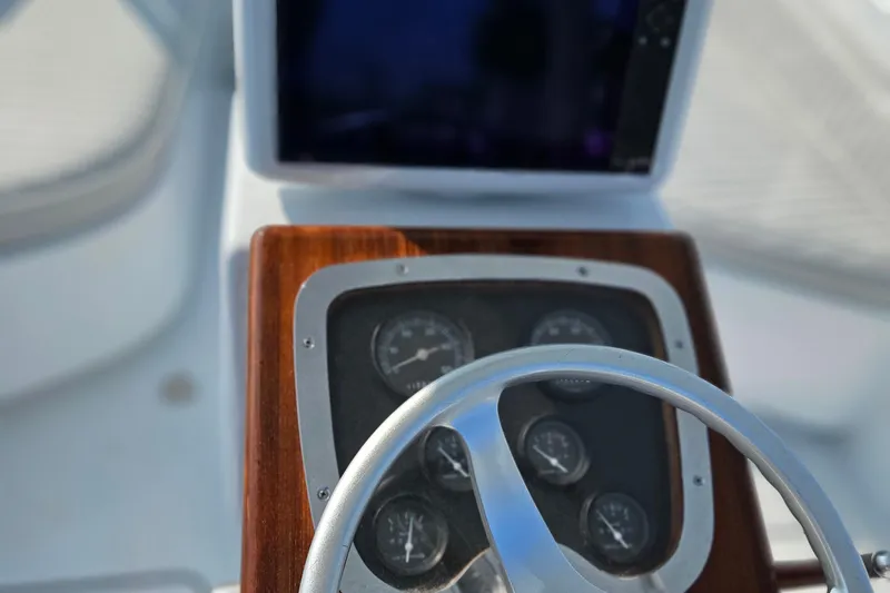 Slide: The Image of Steering wheel and dashboard of 1994 Tides 27 Sportfish boat, featuring gauges and a display. - 4