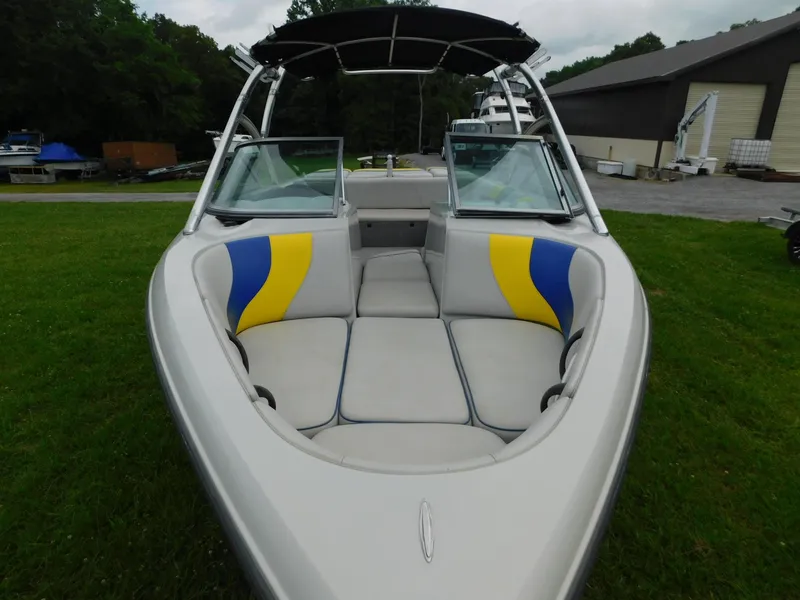 Slide: The Image of 2004 Moomba 23XLV boat with open bow seating, yellow and blue accents, parked on grass. - 11