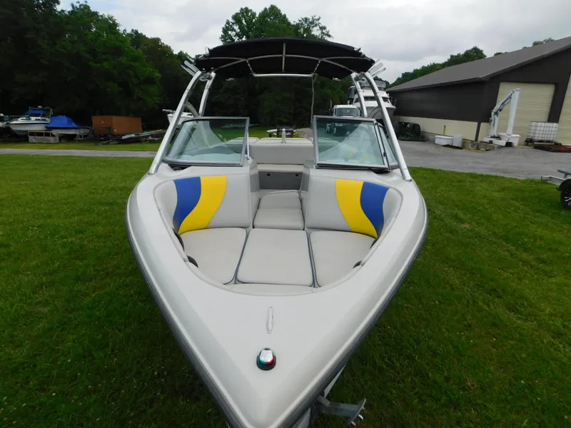 Slide: The Image of 2004 Moomba 23XLV boat with colorful seating, parked on grass near a building. - 12