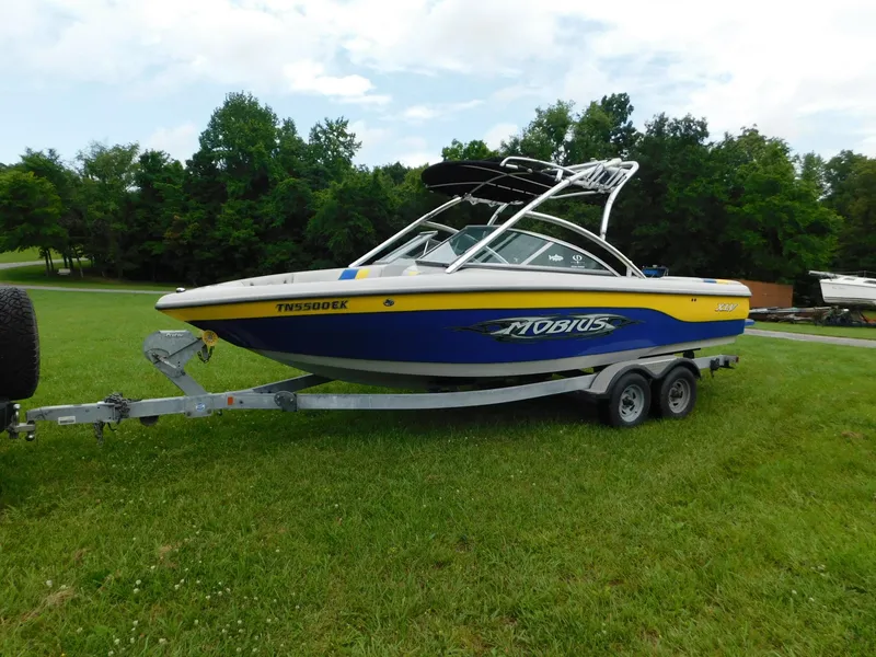 Slide: The Image of 2004 Moomba 23XLV boat on trailer, parked on grass with trees in background. - 2