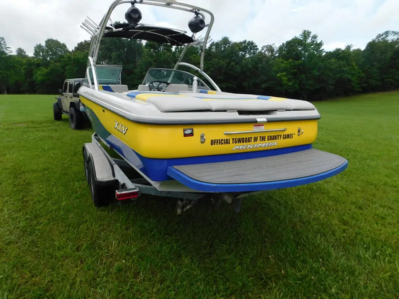 Slide: The Image of 2004 Moomba 23XLV boat on trailer, yellow and blue, parked on grass. - 3