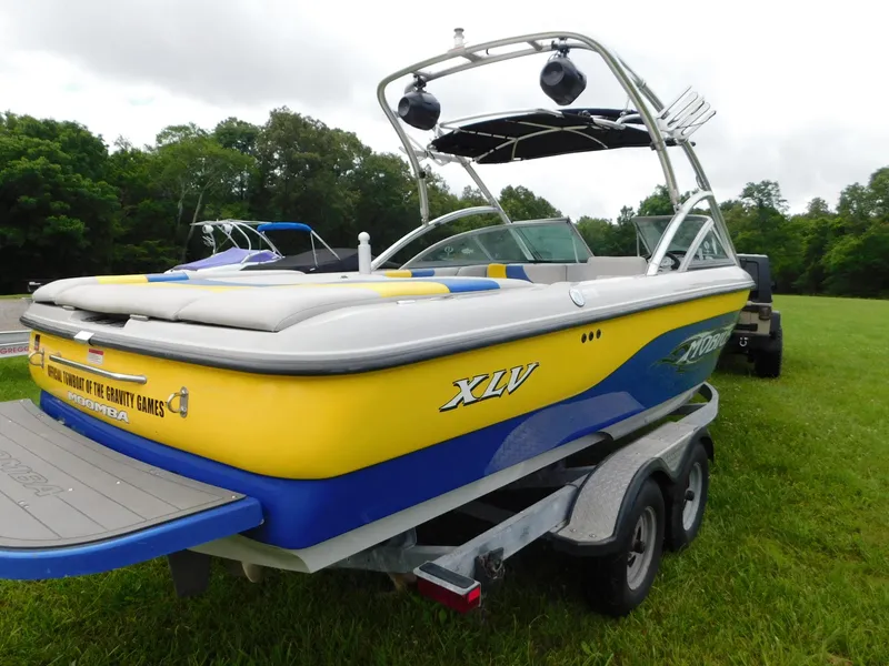 Slide: The Image of 2004 Moomba 23XLV boat on trailer, yellow and blue design, parked on grass. - 6