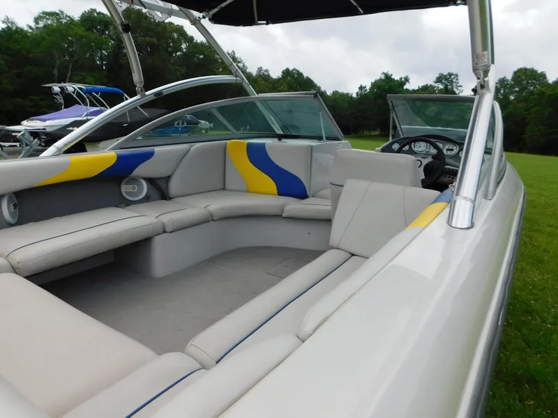 Slide: The Image of 2004 Moomba 23XLV boat interior with gray seating, blue and yellow accents, and open cockpit. - 7