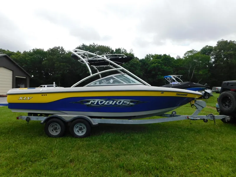 Slide: The Image of 2004 Moomba 23XLV boat on trailer, blue and yellow design, parked on grass. - 9