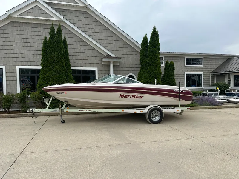The Image of 1999 MasterCraft MariStar 210 VRS boat on trailer, parked outside a building. - 0