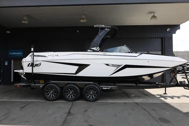 The Image of 2025 Tigé 24RZX boat on trailer, sleek design, parked in a garage. - 1