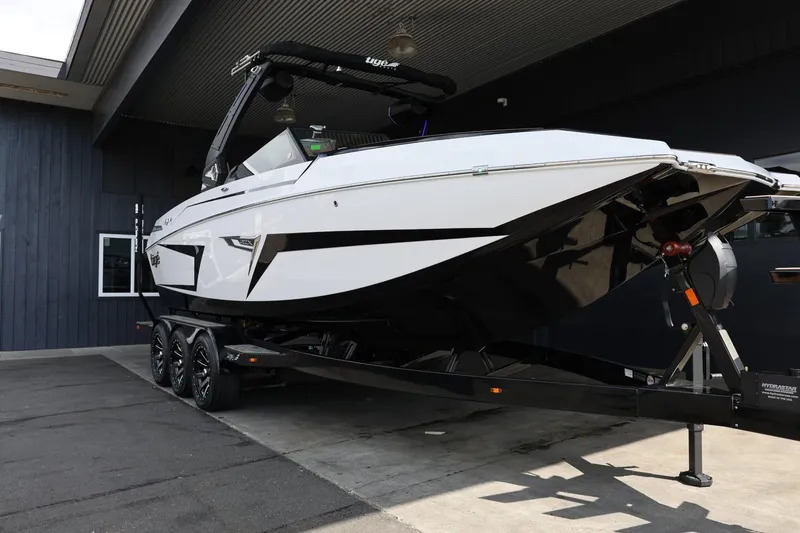 Slide: The Image of 2025 Tigé 24RZX boat on trailer, sleek design, parked under a roof. - 2