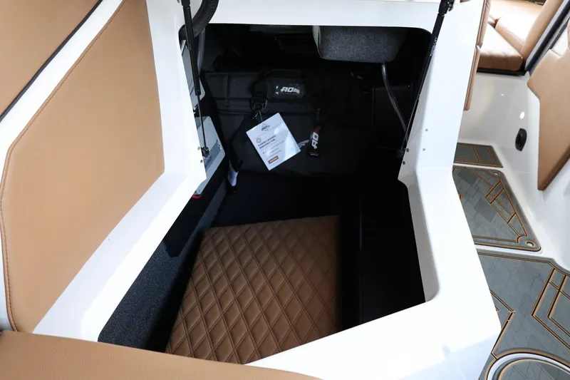 Slide: The Image of 2025 Tigé 24RZX boat interior storage compartment with tan upholstery and diamond-patterned cushion. - 42
