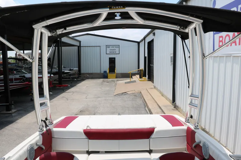 Slide: The Image of 2014 Bayliner 185 BR boat interior with red and white seating, docked near storage facility. - 20