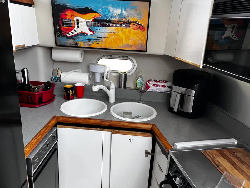 Slide: The Image of 1991 Bayliner 4387 Motoryacht kitchen with modern appliances and vibrant guitar artwork. - 4
