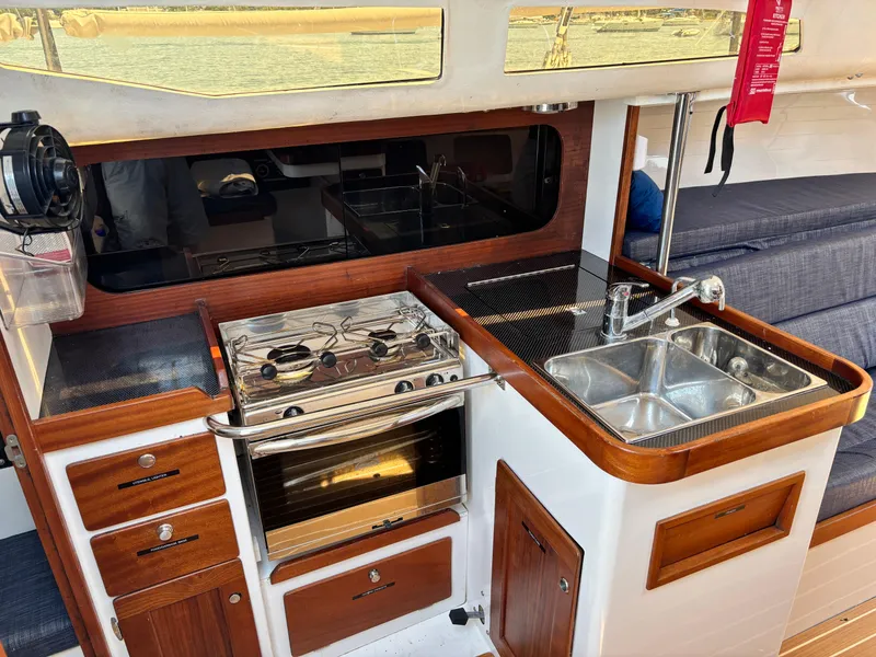 Slide: The Image of 2018 J Boats J/121 yacht interior kitchen with stove, sink, and wooden cabinetry. - 26