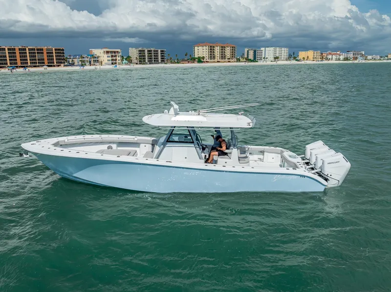 The Image of 2024 Yellowfin 39 boat cruising on ocean near coastal buildings under cloudy sky. - 0