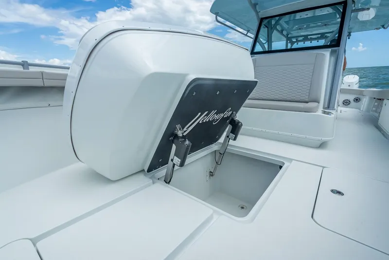 Slide: The Image of 2024 Yellowfin 39 boat deck with storage compartment and seating, under a clear blue sky. - 49