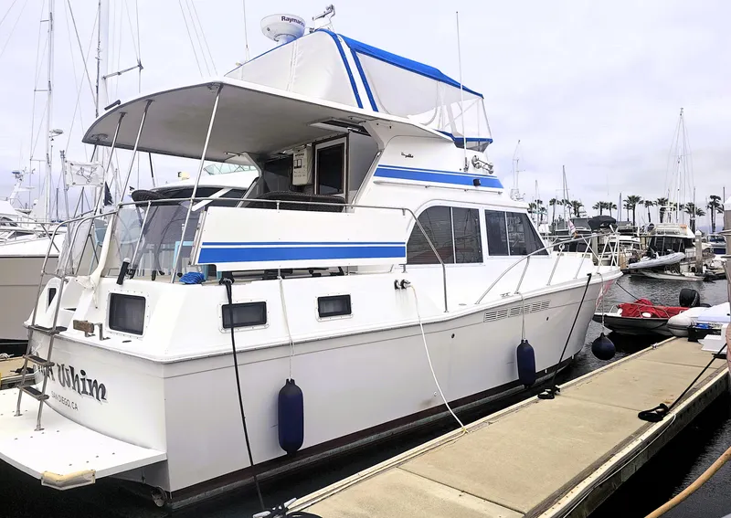 The Image of 1984 Uniflite 42 Double Cabin yacht docked at marina, featuring blue accents and spacious design. - 0