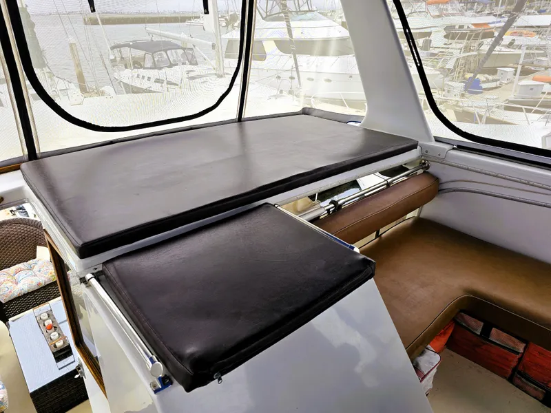 Slide: The Image of 1984 Uniflite 42 Double Cabin interior with cushioned seating and table, docked at marina. - 29