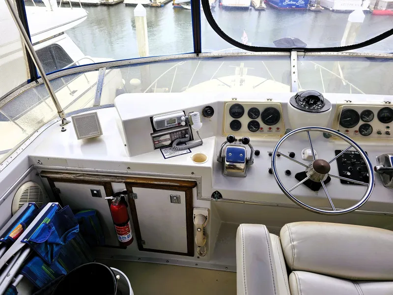Slide: The Image of 1984 Uniflite 42 Double Cabin helm with steering wheel, gauges, and marina view. - 32