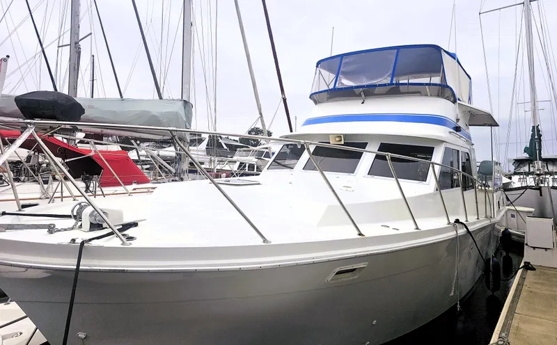 Slide: The Image of 1984 Uniflite 42 Double Cabin yacht docked at a marina, featuring a spacious deck and blue canopy. - 37