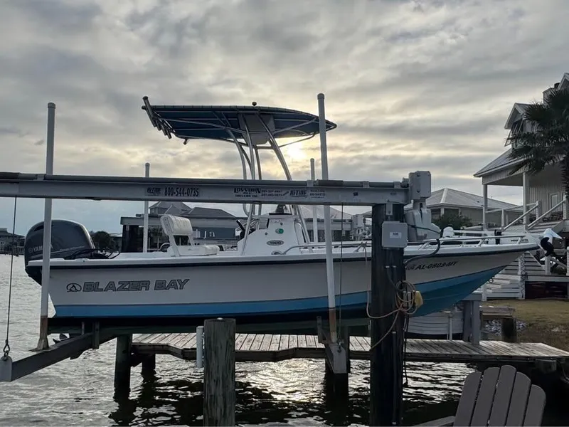 The Image of 2017 Blazer Bay 1900 boat on lift at waterfront dock, cloudy sky background. - 2