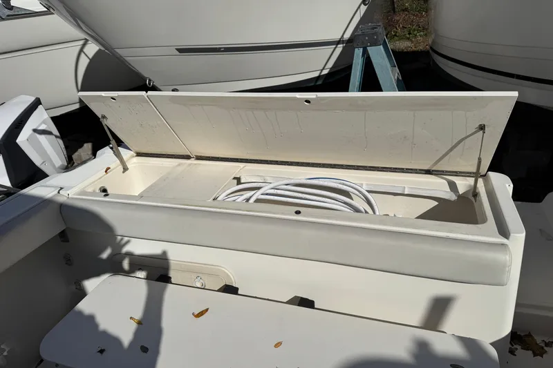 Slide: The Image of Open storage compartment on a 1998 Pursuit 2800 Walkaround boat with coiled hose inside. - 10