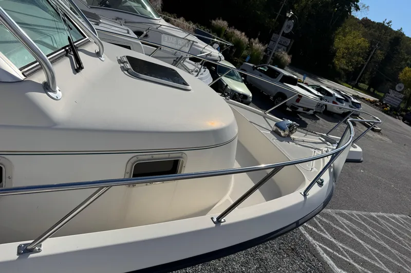 Slide: The Image of 1998 Pursuit 2800 Walkaround boat docked, showcasing sleek design and sturdy railings. - 11