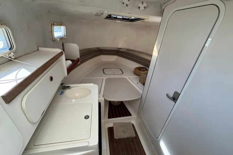 Slide: The Image of 1998 Pursuit 2800 Walkaround cabin interior with sink, table, and storage. - 13