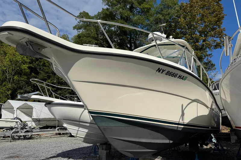 Slide: The Image of 1998 Pursuit 2800 Walkaround boat on dry dock, surrounded by trees and other vessels. - 3