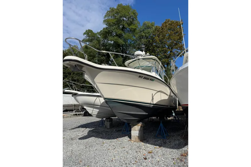 Slide: The Image of 1998 Pursuit 2800 Walkaround boat on stands, surrounded by trees and clear sky. - 4