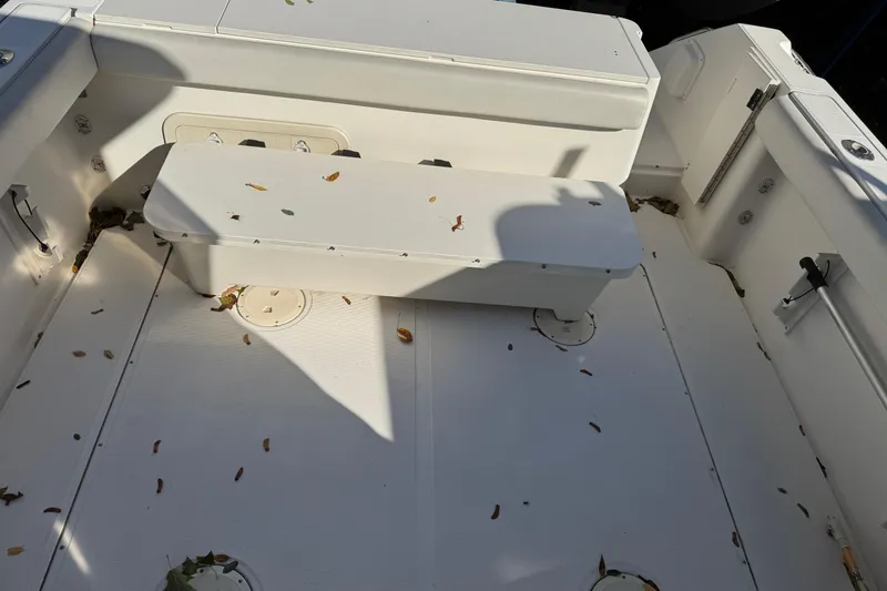 Slide: The Image of 1998 Pursuit 2800 Walkaround boat interior with bench seating and scattered leaves. - 9