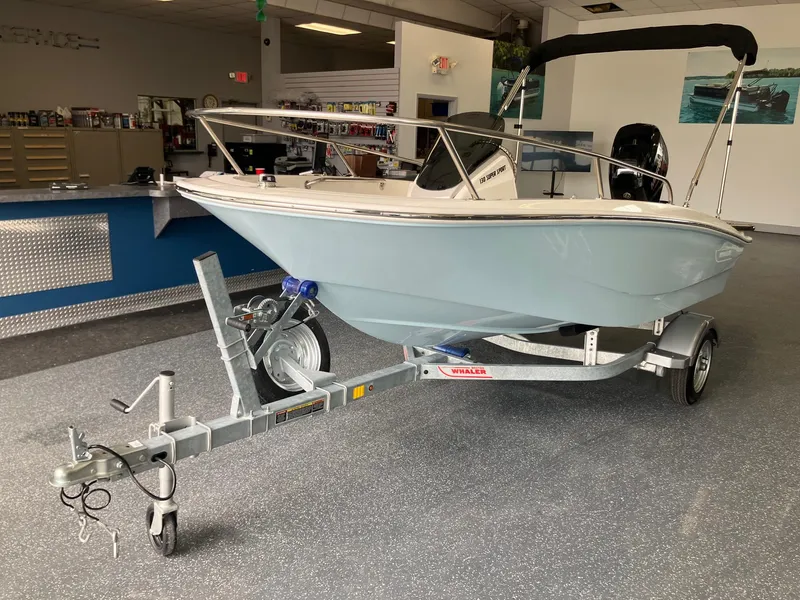 Slide: The Image of 2025 Boston Whaler 130 Super Sport boat on trailer in showroom. - 2