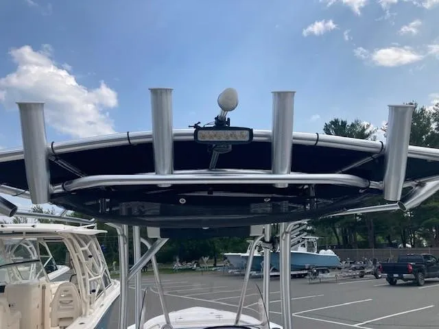 Slide: The Image of 2024 Sea Hunt Ultra 229 boat with T-top and rod holders in a parking lot. - 11