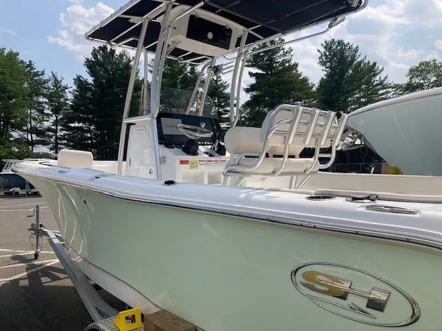 Slide: The Image of 2024 Sea Hunt Ultra 229 boat with T-top and seating, parked outdoors. - 2