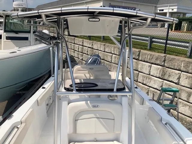 Slide: The Image of 2024 Sea Hunt Ultra 229 boat with T-top and seating, docked near a stone wall. - 6