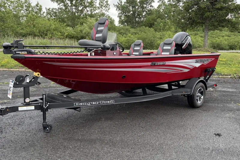 Slide: The Image of 2025 Ranger VS1682SC Reata boat in vibrant red on a trailer, parked outdoors. - 2