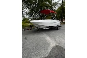 Slide: The Image of 2025 Tahoe T16 boat with red canopy on trailer, parked outdoors. - 2